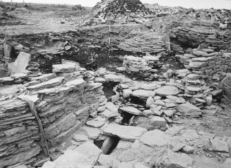 Excavation photograph : South settlement and drain over extended entrance, flagged oval enclosure
