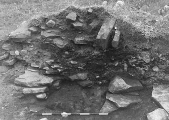 Trench 1, Area A, Feature 4, hearth with flagged surround, underlying East wall of outbuilding.  From West.
