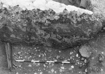 Trench 1, Area A, Feature 3, after cleaning, showing relationship_of upright slab, North wallface, possible end packing stone, cobble layer and pot in section 2.  From North wall of outbuilding.