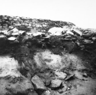 Excavation photograph - trench 1, area A, extension - showing outer face of N wall of outbuilding, from N.
Photographic copy of polaroid print. Copied 1995.