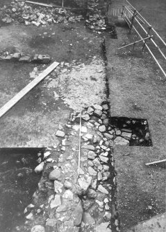 Excavation photograph : W side of E range showing remnants of W wall built on bedrock, from N.