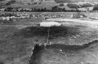 Excavation photograph : pyre site with cist slab beyond.