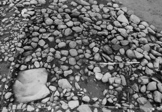 Excavation photograph : cairn from above - cleaned to structure level, and cist slab, north-east quad.