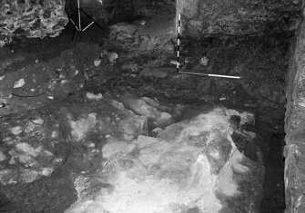 Excavation photograph : area A - offset plinth footing for east wall of chamber sealing stepped, worn rock.