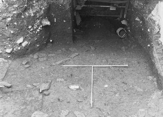 Excavation photograph: area X/H - stone features just emerging from pinkish brown clay, from south.