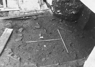 Excavation photograph: area X/H - stone features just emerging from pinkish brown clay, from east.