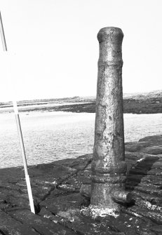 View of iron cannon used as a bollard at pier end.