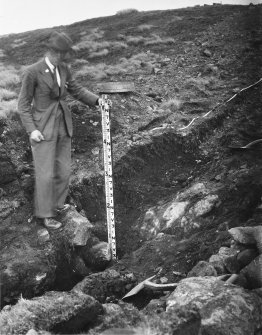 View of excavation trench with rock face and scale.