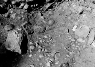 Excavation photograph : f029, pebble floor and 030, slabs and boulders lining pit 021.