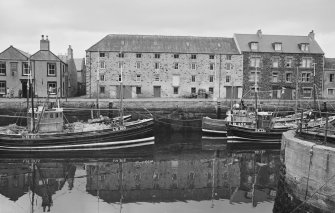 General view of Harbour Road, Eyemouth showing warehouse of T & J Weatherhead, The Ship Hotel, Royal National Mission to Deep Sea Fishermen, Colinville and fishing boats from S.