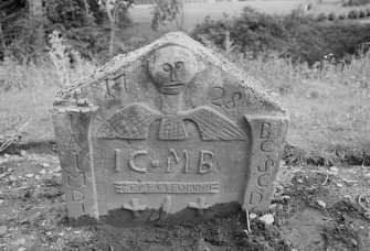 View of gravestone commemorating James Carmichael, 1724, with winged soul above 'Memento Mori' ribbon, two crosses and the sock and coulter of a plough, in the churchyard of Forgandenny Parish Church