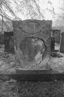 View of E face of headstone commemorating J.V. and M.J., 1726, in the churchyard of Bo'ness Parish Church, showing double cartouche with leafy borderings, one over the other, with revised inscription.