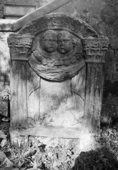View of gravestone commemorating James Craigie, d.1713, in the churchyard of Glencorse Old Parish Church, showing pair of cherubs in pediment and inscription panel flanked by Corinthian pilasters.
