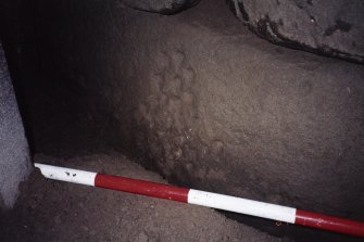 Cup-marked boulder on S side of passage