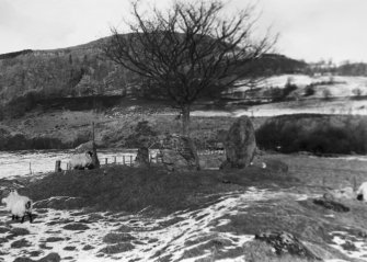 General view of stone circle in snow, hills in background.