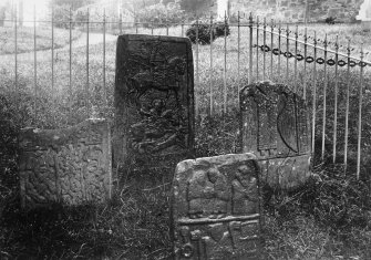 View of four early medieval cross slabs: Kirriemuir nos . 1, 2, 3, 4, in railed enclosure in cemetery.
