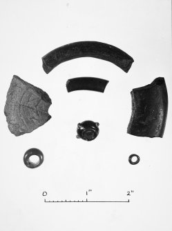 Post ex photograph : three fragments of black shale armlets, part of a stone toggle, and three beads.