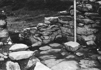 Excavation photograph : entrance at period II level with the secondary walling in the outer part of the passage; hearth H II I to the left of the staff.