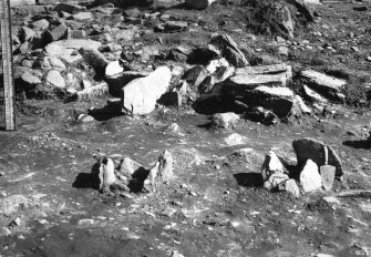 Excavation photograph : sockets exposed at period II horizon, with stone box to right of staff.