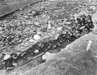 Site X, E facing section of N/S 1m trench, showing slope of cairn from S edge to approximately 1m in front of stone A