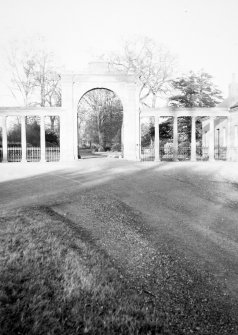 View of entrance archway and colonnade screens from approach drive from S.