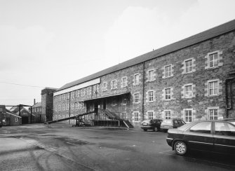 Selkirk, Dunsdale Haugh, Dunsdale Road, Riverside Mills
View from north east of south east side of original spinning mill, with the engine-house in the background. At the time of the survey, the mill was used predominantly as a warehouse, and a mobile chute can be seen permitting the rapid loading of lorries