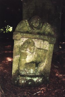 Minto House, Church and Graveyard.
18th century gravestone for William Dods, Helen Dods and six of their children.View of front of gravestone. The carving on the stone depicts a person holding a book with an angel with wings at the top of the stone. At the bottom a hammer, horseshoe and tongs are visible.