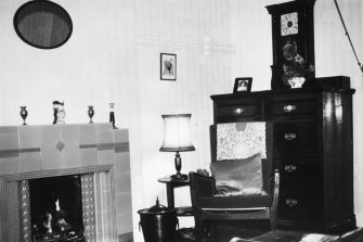 Interior.
View of living room showing chimneypiece, mirror, chair, chest of drawers and wall clock.