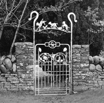 Detail of wrought iron gateway to garden on E side of road with crook and lambs overthrow, 'C H' monogram and naturalistic plant forms.
