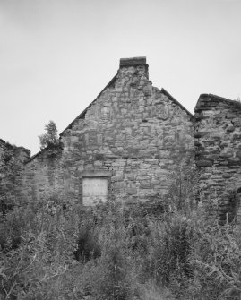 View from NE of warehouse gable, seen from yard formed by ruinous remains of buildings at the N end of the range