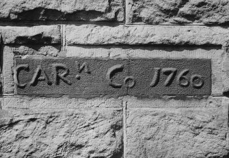 Fragment of inscribed cast-iron furnace lintel preserved in E wall of office block.