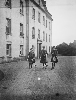 View from S of entrance front,  with three kilted men carrying guns.