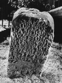 View of eighteenth century inscription on front face of reused medieval gravestone set on end.