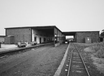 View from SW of railway dispatch buildings [V1, V2 and V9], latterly converted for road transport. View also shows examples of bogeys used on narrow gauge railway throughout plant.
