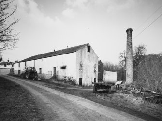 General view from SE of S side of main block of farm buildings (former distillery), including ornate brick chimney stack.