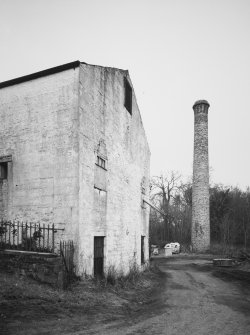 View from S of ESE gable at E side of main block of farm buildings (former distillery), including ornate brick chimney stack in background.