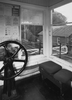 View of interior of signal box showing wheel used to open and close level crossing gates.