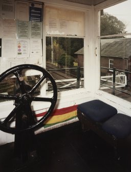 View of interior of signal box showing wheel used to open and close level crossing gates.