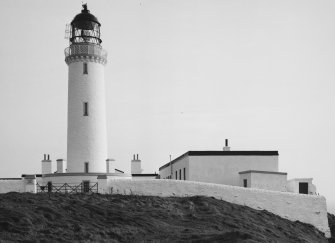 View from SW of lighthouse compound, showing outer wall, main gate, tower, and fog-horn engine house block (right).