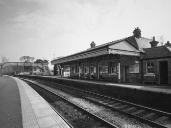 View from NW of S-bound platform, station offices and awning, with footbridge beyond