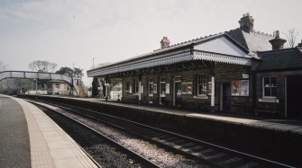 View from NW of S-bound platform, station offices and awning, with footbridge beyond