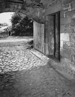 Cobbled entrance to steading with stable door on right, from East