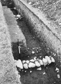 Lyne, Roman fort. Excavation photograph: section across E rampart showing retaining kerbs.
