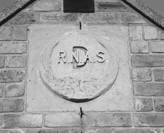 Donibristle airfield, detail of date plaque on gable end of South entrance (building D) to officers' mess.  The plaque has been made of moulded concrete.