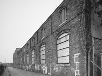 View from North East of South East frontage of works (onto Den Road), showing pilasters and segmentally-arched windows with moulded brick arches.  Note that the works was formerly a foundry, but later became a felt mill for Nairn's of Kirkcaldy