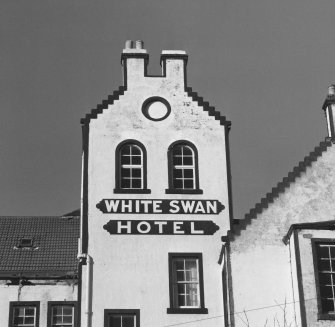 SE front, tower with partially crow stepped gable, blind oculus above double round headed windows above "White Swan Hotel" signage, detail