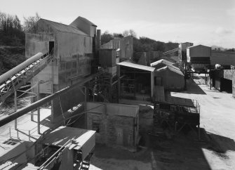 Elevated view from NE (at middle level of shaft kilns) of W end of lime works, showing part of dryer and hammer mill (left), and ball mills in background (centre)