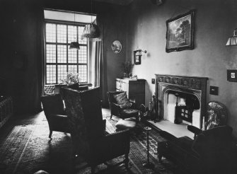 View of drawing room showing fireplace, items of furniture and window.