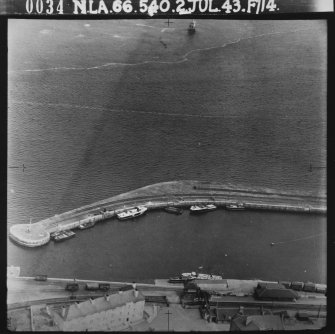 RAF WWII oblique aerial photograph of Tayport Harbour.  Visible is the outer pier and Tayport Railway Station.  In addition several RAF rescue launches are visible alongside the outer pier and main jetty.