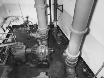 Aberdeen, York Place, Hall Russell Shipyard.
View into underground pump room for dry dock, at West end of mouth of dock. It contains 2 electrically-powered pumps mounted on welded steel beds. Also visible are hand-operated gate valves in discharge pipes (0.53m diameter). Intake pipes are below pump. The pumps were made by Weir Pumps of Glasgow, and the electric motors by Brooks of Huddersfield (150hp). Two smaller pumps remove seepage.